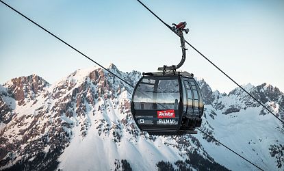 Schwarze Gondel Hartkaiserbahn in Ellmau mit dem verschneiten Wilden Kaiser im Hintergrund