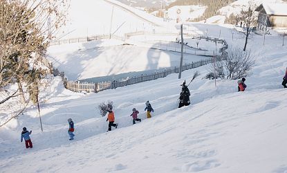 Die Hexen gehen mit den Kindern durch den verschneiten Winterwanderweg.